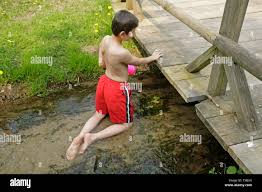 young boy kneeling in a stream Stock Photo - Alamy